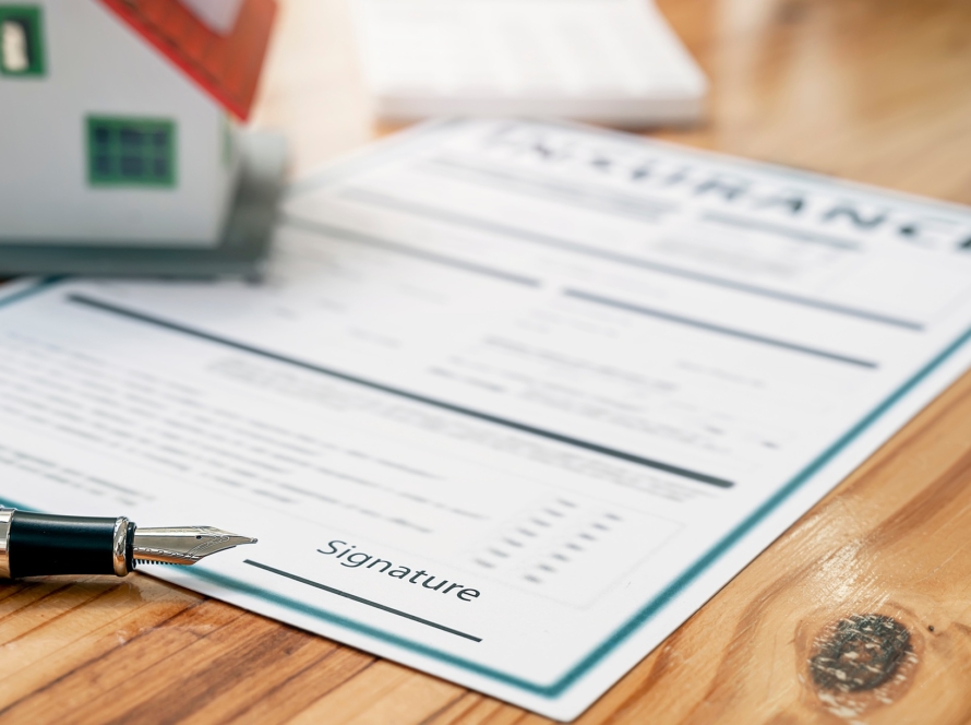 Closeup pen and house model on Insurance policy document.