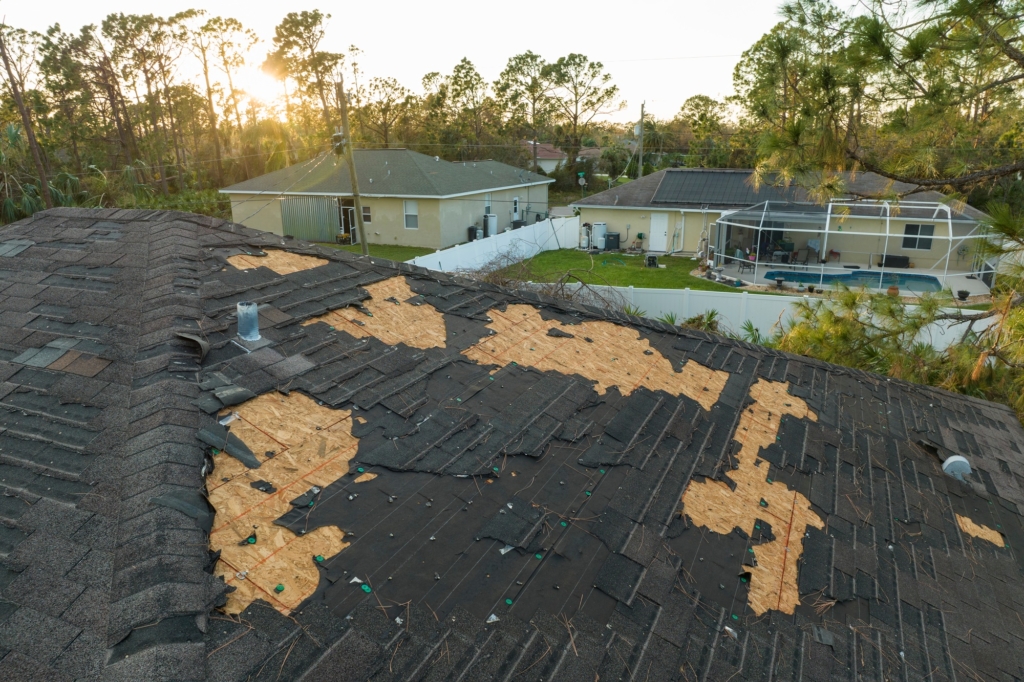 Damaged house roof with missing shingles after hurricane Ian in Florida