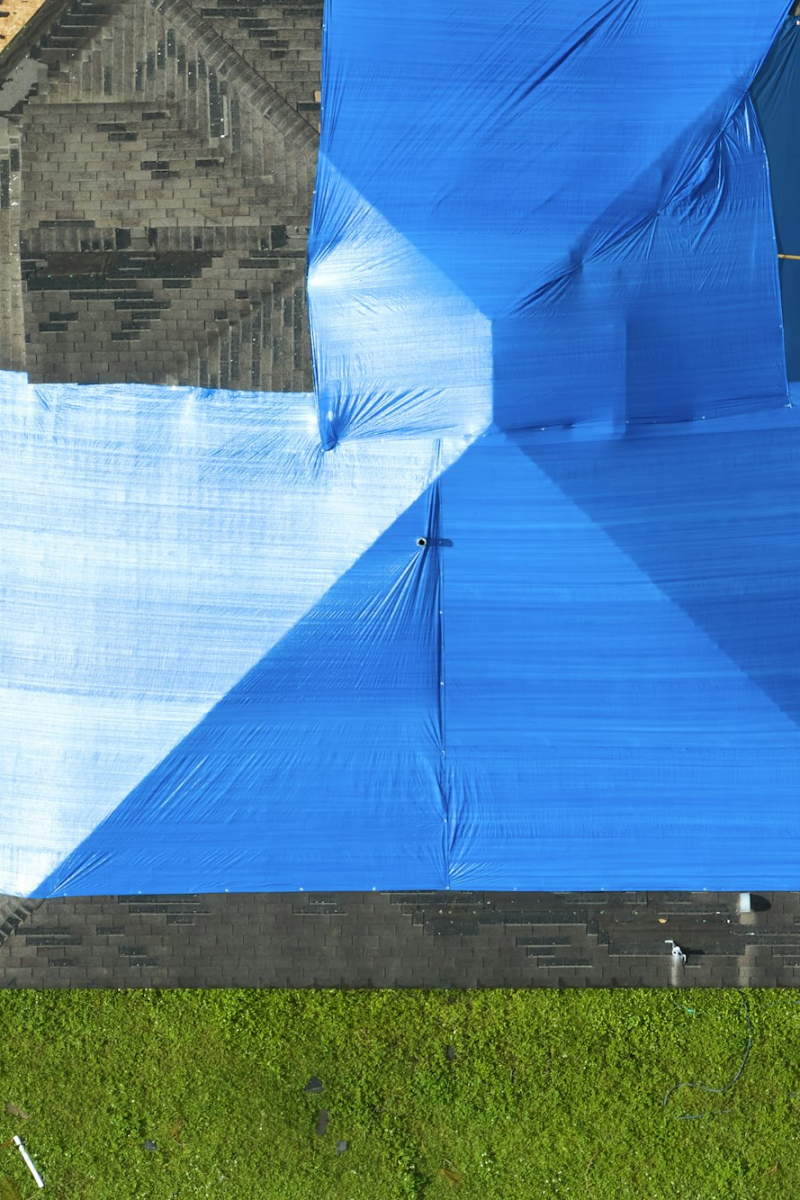 Hurricane Ian damaged house rooftop covered with protective plastic tarp against rain